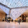 Visitantes bajo la gran pirámide de cristal invertida en el atrio del Museo del Louvre, maravillándose con la arquitectura y disfrutando de su tiempo con la Entrada para el Museo del Louvre sin hacer fila (París). - ForTwo - Planes para parejas