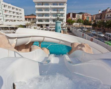 Desde la cima de un emocionante paseo en el Planazo de toboganes y almuerzo buffet en Pineda Splash 30º Hotels en Barcelona, se abre la vibrante escena; una piscina brillante debajo contrasta con edificios distantes y autos estacionados. - ForTwo - Planes para parejas