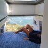 Relajándose en un acogedor Alquiler de furgonetas camper con Mundovan (Badajoz), la persona disfruta de una vista impresionante a través de la puerta trasera abierta, donde la costa rocosa se encuentra con el océano infinito. - ForTwo - Planes para parejas