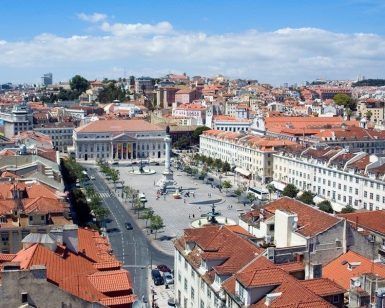 Disfrute de un tour guiado por Lisboa para apreciar plenamente la vibrante vista aérea de la plaza central de la ciudad, rodeada de edificios con techos rojos y contra un cielo azul claro, capturando el encanto de esta impresionante capital portuguesa. - ForTwo - Planes para parejas