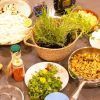 Una acogedora cocina en Sants exhibe una colorida variedad de hierbas, verduras cortadas en cubitos, pollo a la parrilla y salsas variadas con Taller de cocina en Sants con Taller 24, una muestra del encanto culinario de Barcelona. - ForTwo - Planes para parejas
