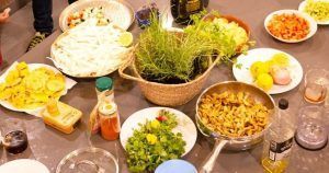 Una acogedora cocina en Sants exhibe una colorida variedad de hierbas, verduras cortadas en cubitos, pollo a la parrilla y salsas variadas con Taller de cocina en Sants con Taller 24, una muestra del encanto culinario de Barcelona. - ForTwo - Planes para parejas