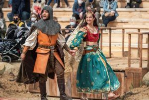 En Puy du Fou España, un hombre con armadura medieval y una mujer con traje tradicional cautivan al público en un evento al aire libre. Los visitantes del parque, cerca de Toledo, viven la historia a través de esta impactante actuación con la Entrada al parque Puy du Fou España (Toledo). - ForTwo - Planes para parejas