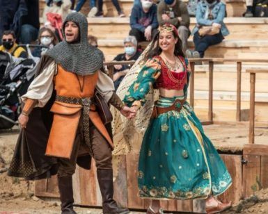 En Puy du Fou España, un hombre con armadura medieval y una mujer con traje tradicional cautivan al público en un evento al aire libre. Los visitantes del parque, cerca de Toledo, viven la historia a través de esta impactante actuación con la Entrada al parque Puy du Fou España (Toledo). - ForTwo - Planes para parejas