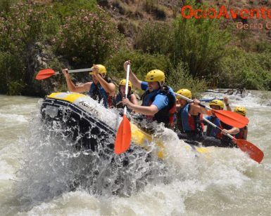Un grupo de aventureros con casco experimentando la emoción del Rafting en el Río Genil - Aguas Bravas, navegando por las salpicadas aguas del río. - ForTwo - Planes para parejas