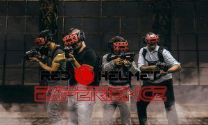 Cuatro personas con gafas VR rojas y equipos en mano se sumergen en la emocionante Red Helmet Experience Realidad Virtual (Barcelona), acompañadas de un texto que ilustra la emoción. - ForTwo - Planes para parejas