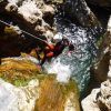 Usando un traje de neopreno, una persona desciende expertamente una cascada hacia una piscina rocosa, abrazando la emoción del Barranquismo en Granada - Tramo medio de Río Verde. - ForTwo - Planes para parejas
