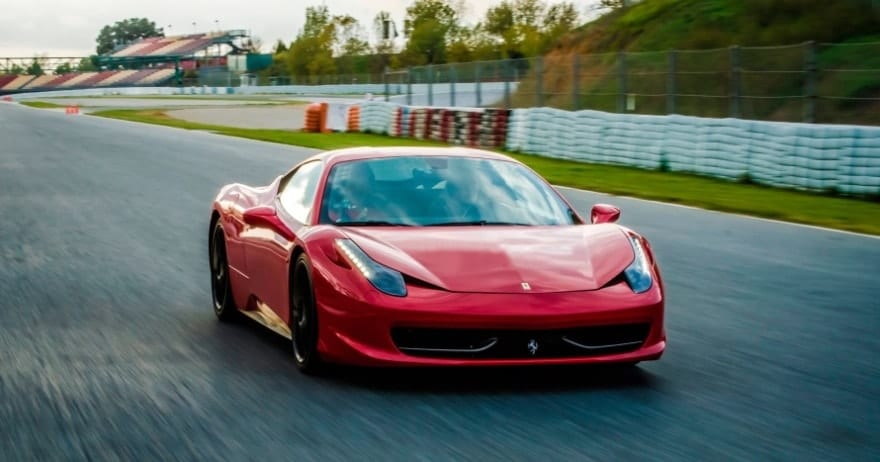 La experiencia "Conduce un Ferrari en Sevilla" ofrece la emoción de conducir un elegante Ferrari en un circuito de carreras, rodeado de exuberante vegetación y barreras para neumáticos. - ForTwo - Planes para parejas