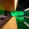 Descubra la "Sensación de serenidad" en el Spa Mandarin Oriental de Barcelona. Disfrute de una moderna piscina cubierta con iluminación ambiental verde, terraza de madera y tumbonas tejidas, dispuestas para capturar la esencia de un tranquilo retiro de spa en cada detalle. - ForTwo - Planes para parejas
