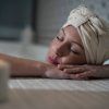 En Le Patio Spa, una persona disfruta de un Ritual Básico con exfoliación, con los ojos cerrados y la cabeza envuelta en una toalla, descansando sobre los brazos cruzados junto a velas encendidas para una relajación máxima. - ForTwo - Planes para parejas