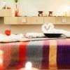 En Magic Experience Urban Spa 1850 Barcelona, disfruta de la relajación con toallas dobladas en forma de corazón sobre una mesa de rayas vibrantes en medio del suave resplandor de las velas y una iluminación tenue. - ForTwo - Planes para parejas