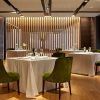 La Cena romántica para dos inolvidables en Beltz (Bilbao) ofrece un entorno elegante con mesas con manteles blancos, sillas de terciopelo verde, detalles en madera e iluminación moderna, ideal para una cena romántica. - ForTwo - Planes para parejas