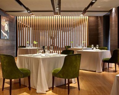 La Cena romántica para dos inolvidables en Beltz (Bilbao) ofrece un entorno elegante con mesas con manteles blancos, sillas de terciopelo verde, detalles en madera e iluminación moderna, ideal para una cena romántica. - ForTwo - Planes para parejas