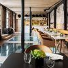 El Restaurante Dos Cielos en Madrid presume de un interior moderno con suelo de cristal, paredes de ladrillo y una elegante iluminación. Las mesas están elegantemente dispuestas con copas y plantas verdes, creando un ambiente refrescante. - ForTwo - Planes para parejas