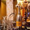 Una botella y una copa de champán de Un Restaurante Küche (Madrid) adornan una mesa elegante, con velas en un candelabro ornamentado que proyectan un brillo cálido, creando un ambiente lujoso similar a una experiencia gastronómica de lujo. - ForTwo - Planes para parejas