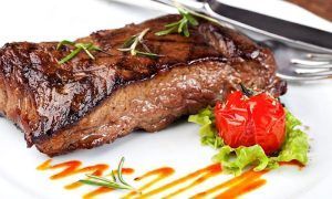 Disfrute de un delicioso filete a la parrilla adornado con romero, tomates cherry y lechuga rociado con salsa en el Restaurante La Oficina en Granada, parte del Menú mediterráneo para dos. - ForTwo - Planes para parejas