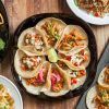 Una variedad de platos mexicanos, incluyendo tacos, papas fritas y ensalada, bellamente dispuestos en una mesa de madera en el Restaurante Mexicano Mr. Uchu en Santander. - ForTwo - Planes para parejas