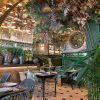 El restaurante Purnima en Madrid, con exuberante vegetación, una decoración elegante, un espejo circular y mesas bien dispuestas, ofrece un entorno tranquilo para saborear el menú de degustación de cocina india. - ForTwo - Planes para parejas