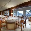 El Menú romántico en el restaurante Abades (Ronda) ofrece una experiencia gastronómica inolvidable con elegantes mesas redondas, sillas de madera, manteles blancos y grandes ventanales que muestran cautivadoras vistas a las palmeras. - ForTwo - Planes para parejas