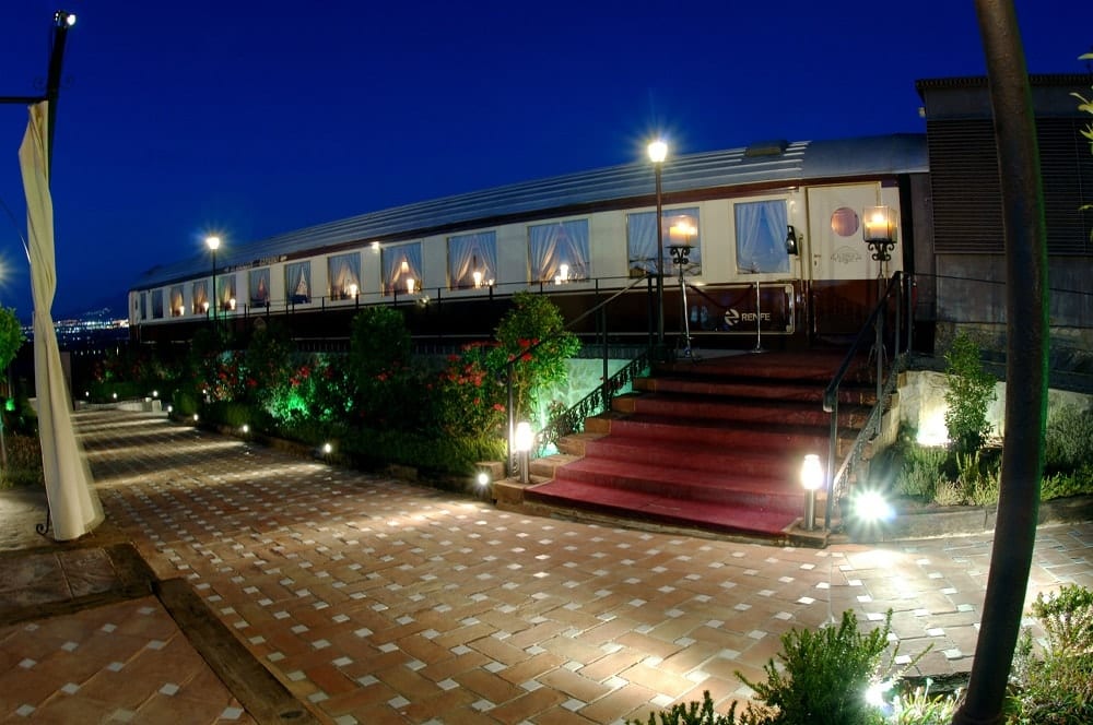 La Oferta Cena romántica en el exclusivo tren histórico Al Ándalus Expreso en Granada ofrece una experiencia gastronómica en vagones de tren antiguos con ventanas iluminadas y una entrada con alfombra roja, perfecta para una cena romántica bajo las estrellas. - ForTwo - Planes para parejas