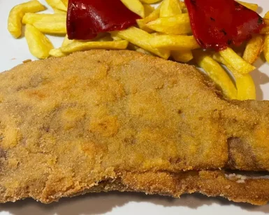 Disfruta del delicioso cachopón, un filete empanizado servido con patatas fritas y pimientos rojos asados como parte de la exquisita "Oferta menú con aperitivo, entrante, cachopón, postre y bebida" en Valverde (Madrid). - ForTwo - Planes para parejas