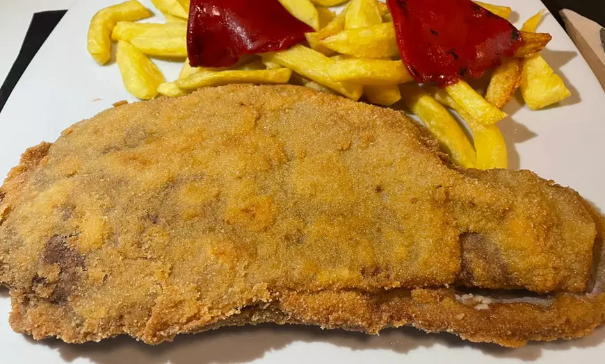 Disfruta del delicioso cachopón, un filete empanizado servido con patatas fritas y pimientos rojos asados como parte de la exquisita "Oferta menú con aperitivo, entrante, cachopón, postre y bebida" en Valverde (Madrid). - ForTwo - Planes para parejas