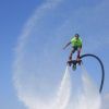 Flotando en las cristalinas aguas de Barcelona, una persona en "Vuela sobre el agua en Hoverboard o Flyboard en Barcelona" crea un patrón circular de rociado contra el cielo azul claro. - ForTwo - Planes para parejas