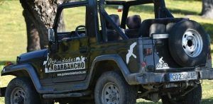 Un Jeep convertible negro, adornado con la marca Actividades Barbancho y símbolos de aventuras al aire libre, está estacionado en el césped, invitando a los exploradores a embarcarse en la emocionante Ruta 4x4 Vía de la Plata y Santuarios (Cáceres). - ForTwo - Planes para parejas