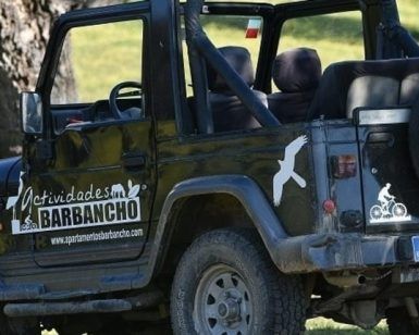 Un Jeep convertible negro, adornado con la marca Actividades Barbancho y símbolos de aventuras al aire libre, está estacionado en el césped, invitando a los exploradores a embarcarse en la emocionante Ruta 4x4 Vía de la Plata y Santuarios (Cáceres). - ForTwo - Planes para parejas