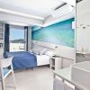 Disfrute de una habitación moderna en el Escapada Hotel Ryans La Marina con cama doble, detalles en azul, obras de arte playeras y balcón con vistas al mar. Disfrute del ambiente ibicenco con desayuno incluido para empezar el día. - ForTwo - Planes para parejas