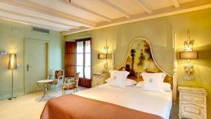 Disfrute de una elegante habitación ideal para una escapada en una encantadora casa del siglo XVIII, con cama doble, decoración vintage, iluminación tenue y vigas de madera. Disfrute del desayuno en la mesa redonda junto a la ventana. Nombre del producto: Escapada con desayuno y botella de cava a una casa del siglo XVIII (Sevilla). - ForTwo - Planes para parejas