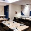 El comedor luce arte mural geométrico, mesas de madera y platos y vasos cuidadosamente colocados. Disfrute del sabor griego en el Restaurante Griego Kuzina en Valencia, donde la elegancia mediterránea se fusiona con el diseño contemporáneo para una comida inolvidable. - ForTwo - Planes para parejas