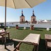 Disfruta de una tranquila mañana en la azotea con el desayuno de "Escapadita a San Fernando con desayuno, cava y bombones (Cádiz)". Relájate bajo una sombrilla entre tumbonas y exuberante vegetación, contemplando el vibrante paisaje urbano de Cádiz y las majestuosas torres de la iglesia de San Fernando a lo lejos. - ForTwo - Planes para parejas