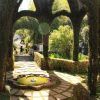 Este jardín, como una joya escondida que recuerda al encantador barrio del Albaicín de Granada, cuenta con una estructura de seto arqueada, una fuente circular y un camino de piedra rodeado de exuberante vegetación: una escapada tranquila similar a la experiencia de la Visita al Albaicín y Sacromonte. - ForTwo - Planes para parejas