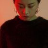 En IM Estudio de Madrid, bajo una dramática iluminación roja y verde, una mujer que viste un suéter negro peludo y pendientes de aro mira hacia abajo en una impactante fotografía de estudio. - ForTwo - Planes para parejas