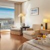 La encantadora habitación del Hotel SH Valencia Palace (Valencia) incluye una cómoda cama, elegantes sillas y una mesa junto a la ventana con vistas a la ciudad. Una bandeja de desayuno repleta de deliciosos dulces le espera en la cama. - ForTwo - Planes para parejas