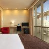 Alójese en una elegante habitación del Hotel Silken Puerta de Valencia con una cama grande, escritorio y silla roja. Disfrute de su café matutino en el balcón mientras disfruta de las soleadas vistas a través de las puertas de cristal, ideal para su visita. - ForTwo - Planes para parejas