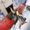 Dos personas saltan en paracaidismo en tándem desde un avión rojo, con el cielo azul expansivo y las nubes como telón de fondo: una experiencia Paracaidismo en Barcelona desde 4000 metros - BCN SkyDive impresionante. - ForTwo - Planes para parejas
