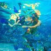 Dos personas practican snorkel en las cristalinas aguas de Herradura, rodeadas de peces vibrantes. Su aventura "Buceo Snorkel en la Herradura y Almuñécar (Granada)" revela la belleza submarina oculta. - ForTwo - Planes para parejas
