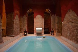 Experimente una lujosa piscina cubierta con arcos de ladrillo, iluminación tenue y linternas en "Un baño árabe en privado en pareja en Baños de Elvira (Granada)", creando un ambiente sereno que recuerda a un auténtico retiro de baño árabe. - ForTwo - Planes para parejas