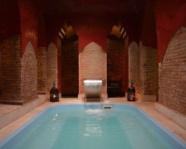 Experimente una lujosa piscina cubierta con arcos de ladrillo, iluminación tenue y linternas en "Un baño árabe en privado en pareja en Baños de Elvira (Granada)", creando un ambiente sereno que recuerda a un auténtico retiro de baño árabe. - ForTwo - Planes para parejas