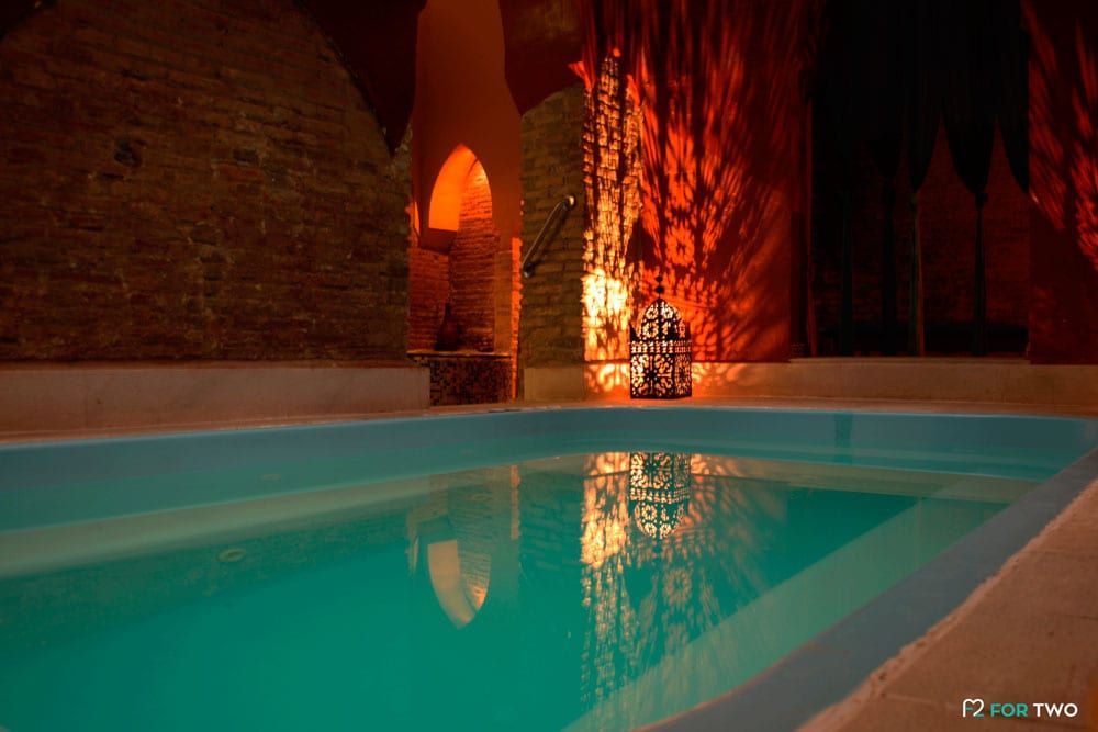La piscina cubierta, que evoca el Baño sencillo de los Baños árabes de Elvira, cuenta con una iluminación cálida que baila sobre las paredes de ladrillo y proyecta sombras encantadoras desde una linterna. - ForTwo - Planes para parejas