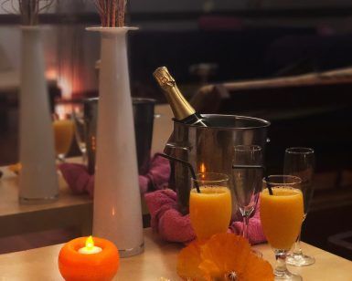 Una acogedora mesa decorada con zumo de naranja, champán, una vela y flores captura el ambiente relajante del Circuito termal de spa - Tratamiento deluxe en Tenerife. - ForTwo - Planes para parejas