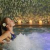 En Barcelona, una mujer se relaja con los ojos cerrados en un jacuzzi de spa, rodeada de velas parpadeantes y mosaicos, disfrutando del ambiente relajante que ofrece el Spa y masaje con velas para dos. - ForTwo - Planes para parejas