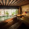 Una acogedora sala de spa con jacuzzi, iluminación ambiental y exuberante vegetación refleja el estilo del Spa y masaje a lo japonés + menú de tapas en Madrid. Faroles rojos decorativos en una pared de piedra aportan un toque elegante. - ForTwo - Planes para parejas