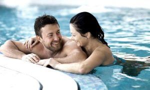 Una pareja sonríe y se abraza junto a una piscina tras disfrutar del "Spa y cena para dos en Spa Bodyna Hospes Puerta de Alcalá" en Madrid. - ForTwo - Planes para parejas