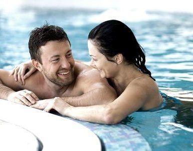 Una pareja sonríe y se abraza junto a una piscina tras disfrutar del "Spa y cena para dos en Spa Bodyna Hospes Puerta de Alcalá" en Madrid. - ForTwo - Planes para parejas