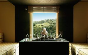 El moderno interior de la sauna cuenta con calefacción central y bancos de madera, lo que proporciona un remanso de paz. La vista a través de la ventana a las verdes colinas evoca la atmósfera relajante del famoso Circuito de Hidroterapia de La Cala Golf Spa Málaga. - ForTwo - Planes para parejas