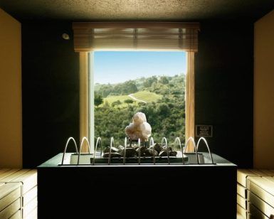 El moderno interior de la sauna cuenta con calefacción central y bancos de madera, lo que proporciona un remanso de paz. La vista a través de la ventana a las verdes colinas evoca la atmósfera relajante del famoso Circuito de Hidroterapia de La Cala Golf Spa Málaga. - ForTwo - Planes para parejas