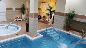 Disfrute de la Oferta de Spa Romántico en pareja con masaje y bebida en Madrid, que cuenta con un jacuzzi interior y una piscina rodeada de plantas en macetas y velas para una máxima relajación y placer. - ForTwo - Planes para parejas